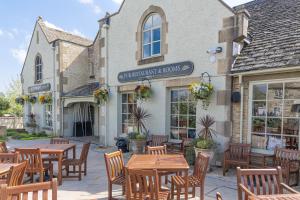 a restaurant with wooden tables and chairs in front of a building at Priory Inn in Tetbury