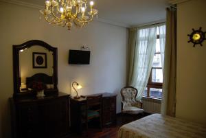 a bedroom with a mirror and a dresser and a chair at Pensión Araba II in Vitoria-Gasteiz