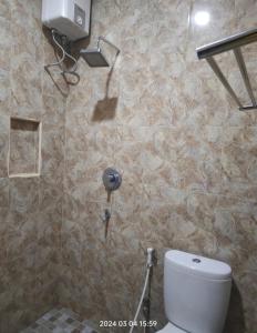 a bathroom with a toilet and a stone wall at Karjo Homestay Syariah in Ngadipuro