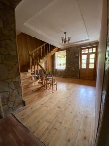 a large living room with wooden stairs and a stone wall at Sofia in Vardzia