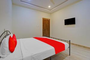 sypialnia z łóżkiem z czerwonymi poduszkami i telewizorem w obiekcie OYO Flagship Hotel Vathsalya w mieście Warangal