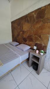 a bed with a table next to a stone wall at Los primos in Búzios