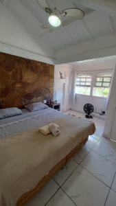 a bedroom with a large bed with a stone wall at Los primos in Búzios