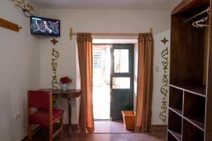 um quarto com uma porta com uma mesa e uma televisão em Hospedaje La Florida em Urubamba