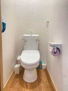 a bathroom with a white toilet and a wooden floor at Guesthouse Takayama Hanzansha in Takayama