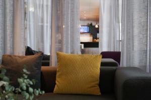 a couch with a yellow pillow in a living room at Comfort Hotel Helsingborg in Helsingborg