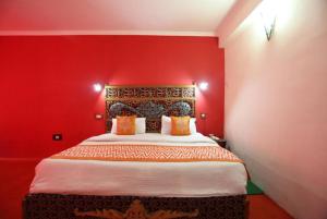 a bedroom with a red wall with a bed at Goroomgo Ishan Resort Near sangor valley-Best Experince Ever in Manāli