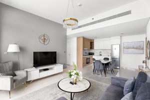 Una sala de estar con un sofá, un televisor y una mesa. en Seaside Serenity: 1-BR Apartment with Beach Access, en Dubái