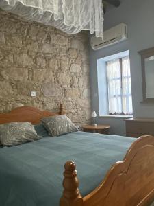 1 dormitorio con cama de madera y pared de piedra en Vasilion Agrotourism, en Polis Chrysochous