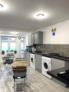 een keuken met een wasmachine en een tafel en stoelen bij Penn Gardens Flat 1 - 2 - 3 & 4 Apartments in Havering atte Bower