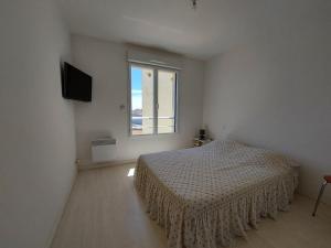 a white bedroom with a bed and a window at La baie de Sion in Saint-Hilaire-de-Riez