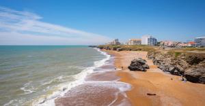 a beach with rocks and the ocean and buildings at La baie de Sion in Saint-Hilaire-de-Riez