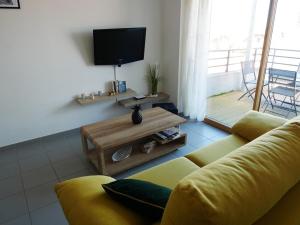a living room with a yellow couch and a television at La perle océane de St Gilles in Saint-Gilles-Croix-de-Vie