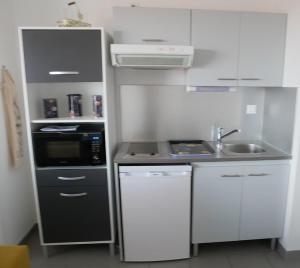 a small kitchen with a sink and a microwave at La perle océane de St Gilles in Saint-Gilles-Croix-de-Vie