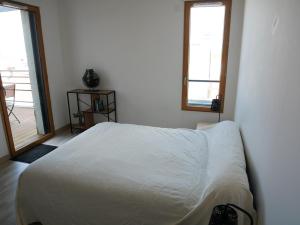 a bedroom with a white bed and two windows at La perle océane de St Gilles in Saint-Gilles-Croix-de-Vie