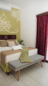 Un dormitorio con 2 camas y un banco. en AMINA Inn en Flores