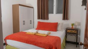 1 dormitorio con 1 cama con almohada roja y toallas en AMINA Inn en Flores