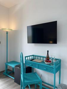 una consola azul con TV y 2 sillas en Hotel Baia Delle Sirene en Taormina