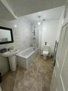 ein Badezimmer mit einer Badewanne, einem Waschbecken und einem WC in der Unterkunft MK Apartments South MCR, Chorlton in Manchester
