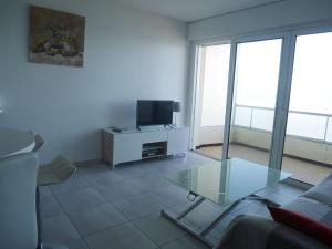 ein Wohnzimmer mit Glastisch und Fernseher in der Unterkunft L'estivant sur l'océan in Saint-Hilaire-de-Riez