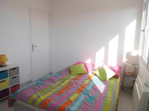 ein Schlafzimmer mit einem Bett mit bunten Laken und Kissen in der Unterkunft L'estivant sur l'océan in Saint-Hilaire-de-Riez