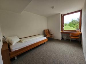 1 dormitorio con cama, ventana y escritorio en Hotel Simplicity by Bad Schönbrunn, en Menzingen