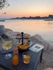 a picnic table with food and drinks on the water at Mobilna kućica Val in Šimuni