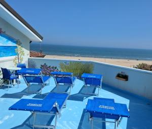 a group of blue chairs and tables on a balcony with the beach at Residence Saturnia in Riccione