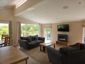 a living room with a couch and a tv on the wall at Wold View Country Park & Fisheries Lodges 1 and 9 in Market Rasen
