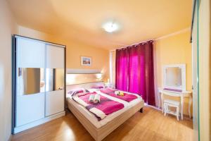 a bedroom with a large bed with pink curtains at Guesthouse Mira in Rab