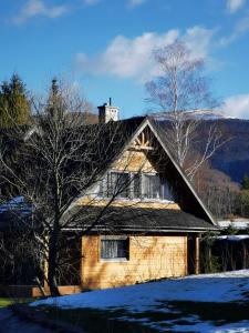 una casa di legno nella neve con un albero di Na Skraju Nieba a Smerek