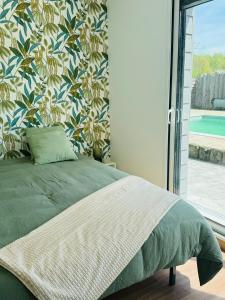 a bedroom with a green bed with a floral wall at le chant de la rivière in Abbeville