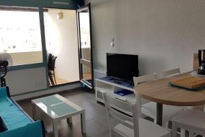 ein Wohnzimmer mit einem Tisch und einem TV in der Unterkunft Studio cabine 4p Proche mer - Piscine - Parking in Cap d'Agde