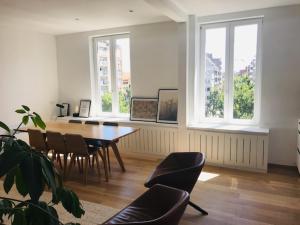 - une salle à manger avec une table, des chaises et des fenêtres dans l'établissement Prachtig gerenoveerd appartement, à Ostende