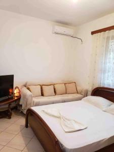 ein Wohnzimmer mit einem Sofa und einem Bett in der Unterkunft Andi's GuestHouse in Sarandë