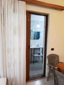 Zimmer mit Spiegel und Tür mit Fenster in der Unterkunft Andi's GuestHouse in Sarandë