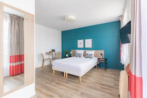a bedroom with a white bed and a blue wall at Appart'City Classic Paris La Villette in Paris