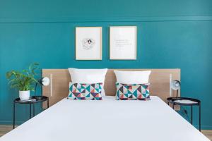 パリにあるAppart'City Classic Paris La Villetteのベッドルーム1室(大型ベッド1台付)が備わります。壁には2枚の写真が飾られています。