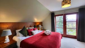 a bedroom with a bed with a red blanket at Red Squirrel Lodge in Boat of Garten