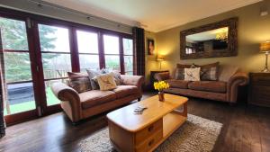 Sala de estar con 2 sofás y mesa de centro en Red Squirrel Lodge, en Boat of Garten