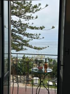 Une porte ouverte s'ouvre sur une terrasse avec une table et l'océan. dans l'établissement Hotel Baia Delle Sirene, à Taormine