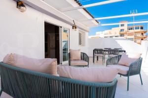 een patio met banken en stoelen op een balkon bij Apartment with terrace steps from beach REMS in Fuengirola