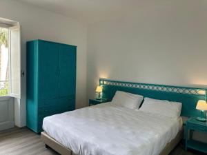 a bedroom with a large bed and a blue cabinet at Hotel Baia Delle Sirene in Taormina