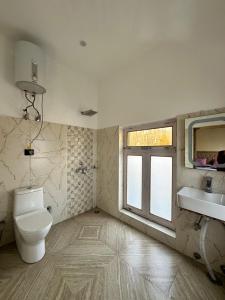 a bathroom with a toilet and a sink and a window at sky land in Leh