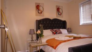 Milton Keynes 3 Bed House في Shenley Church End: غرفة نوم مع سرير مع اللوح الأمامي الأسود وطاولة