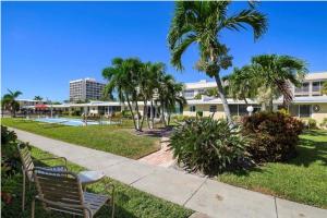 a park with chairs and palm trees in front of a building at Casa Mar By Beachside Management in Sarasota