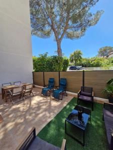 a patio with chairs and a table and a tree at Entre Mer et nature in Saint-Aygulf