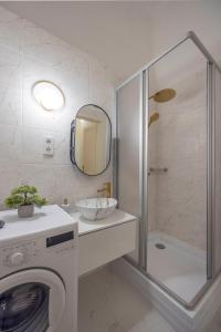 La salle de bains est pourvue d'une douche, d'un lavabo et d'un lave-linge. dans l'établissement Cozy Boulevard Apartment in the Heart of Budapest, à Budapest