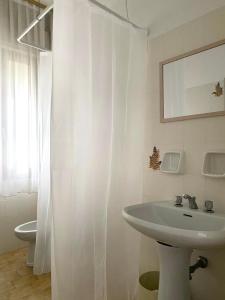 a white bathroom with a sink and a toilet at Hotel Ariston in Sottomarina