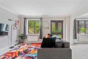 a living room with a couch and windows at The Pondmore-Spacious Detached house in Ashford with free parking close to M20 in Kent
